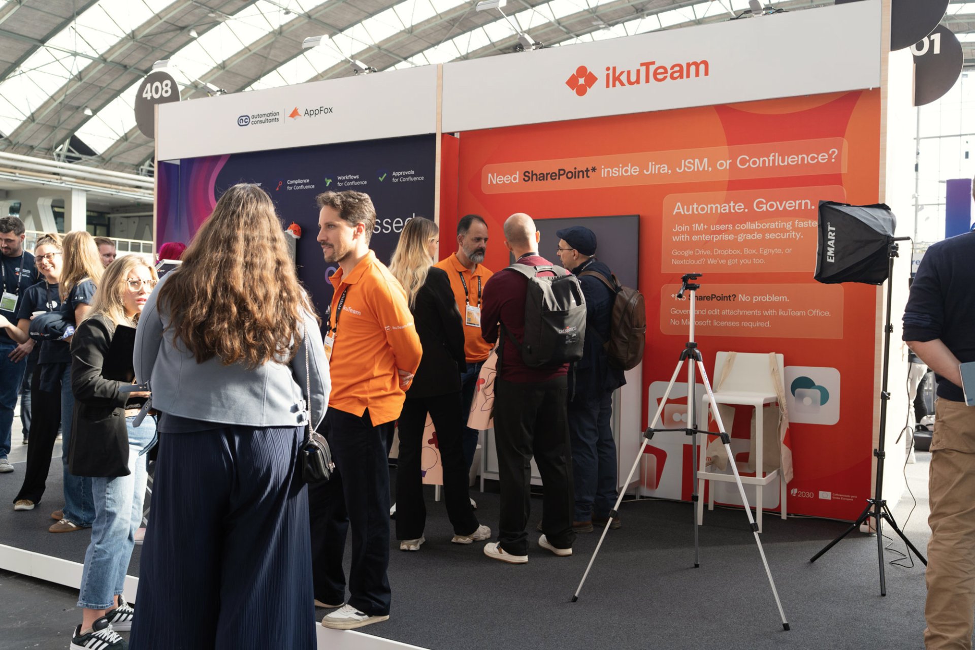 ikuTeam team in orange shirts talking with visitors at booth 407